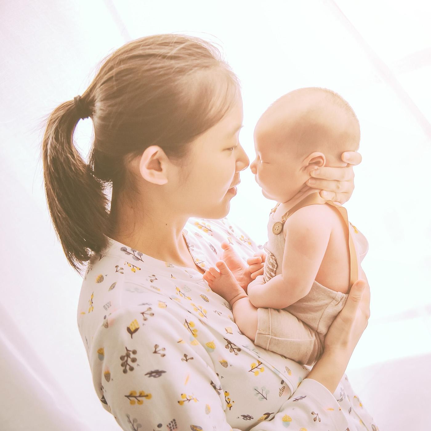 Woman holds up infant in sunlight